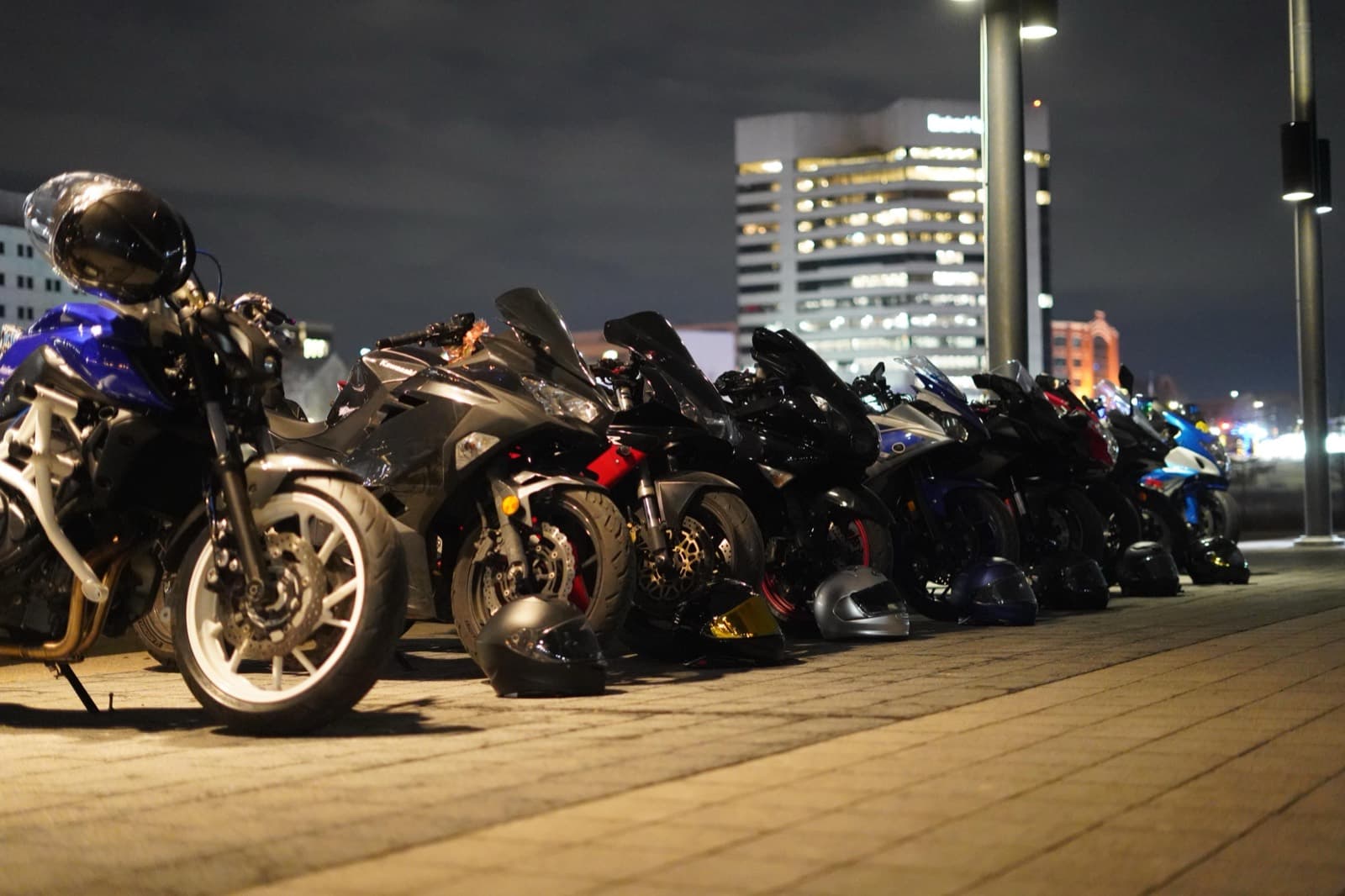Bikes and helmets lined up under city lights at a night meetup
