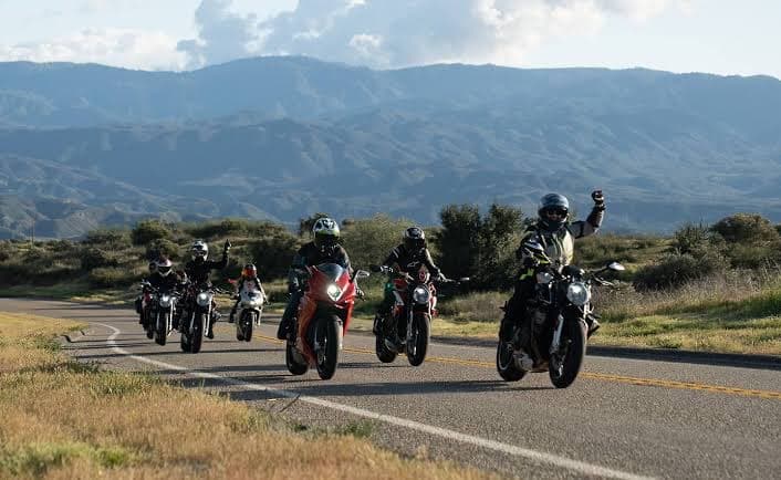 A rider throws a fist up leading a group down a canyon road through the desert mountains