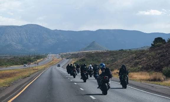 A pack of riders heading down a desert highway toward the mountains