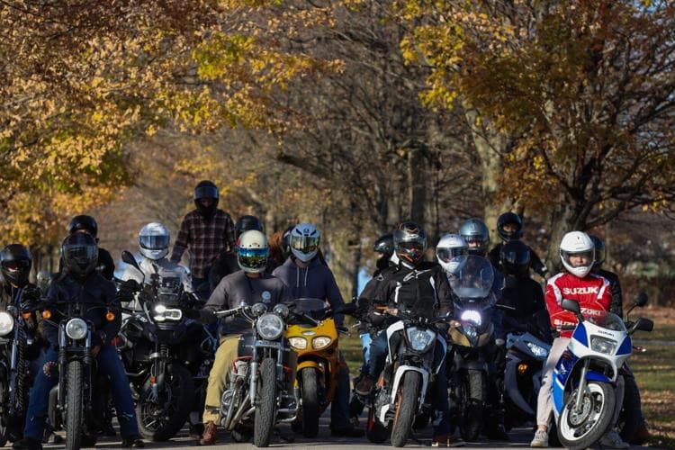 A pack of riders staged and ready to roll out under fall trees