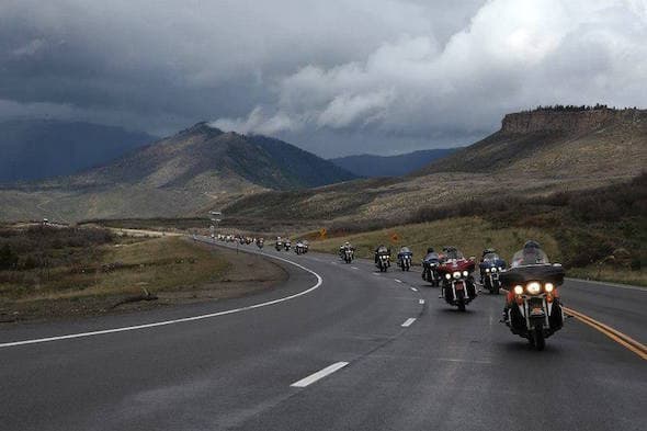 Touring bikes sweeping through a mountain pass under storm clouds