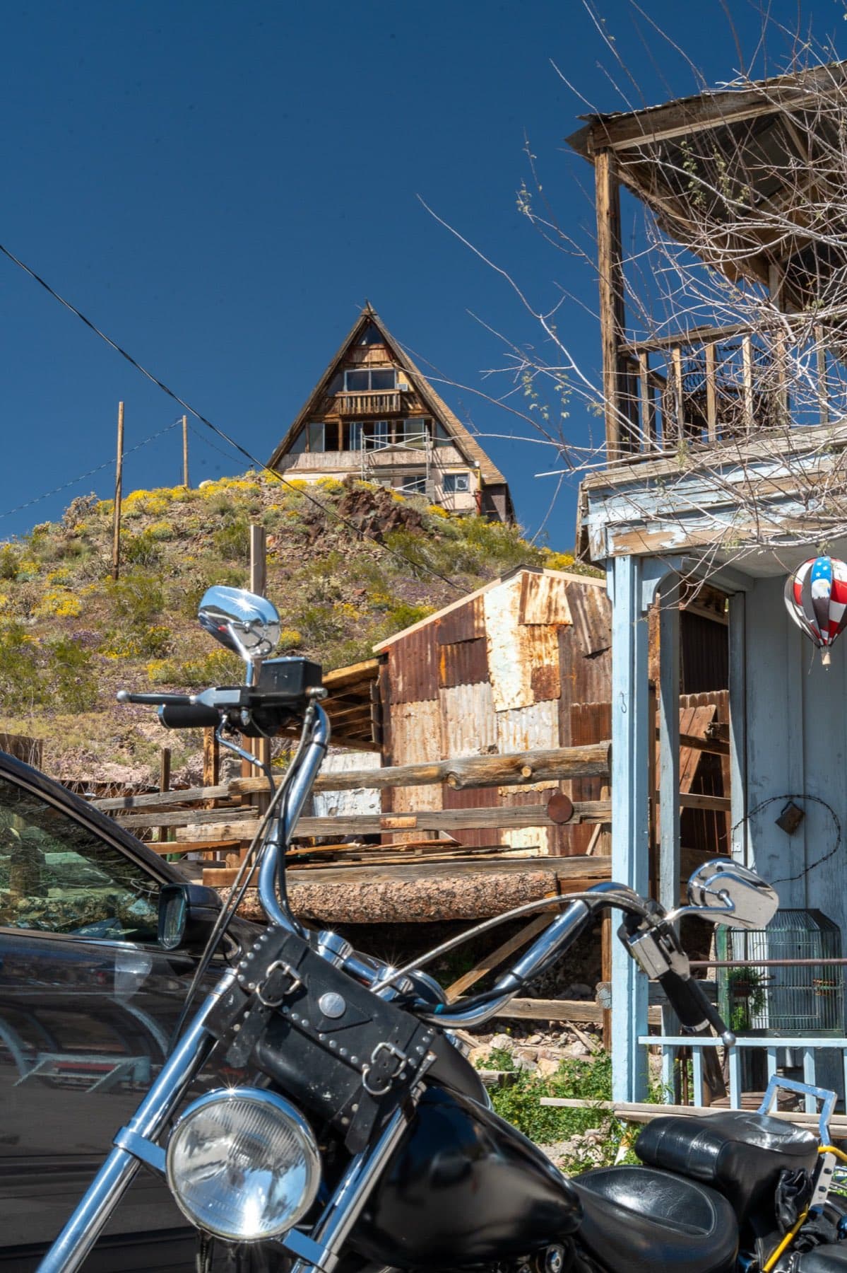 A chopper parked below an old A-frame in the Nevada desert