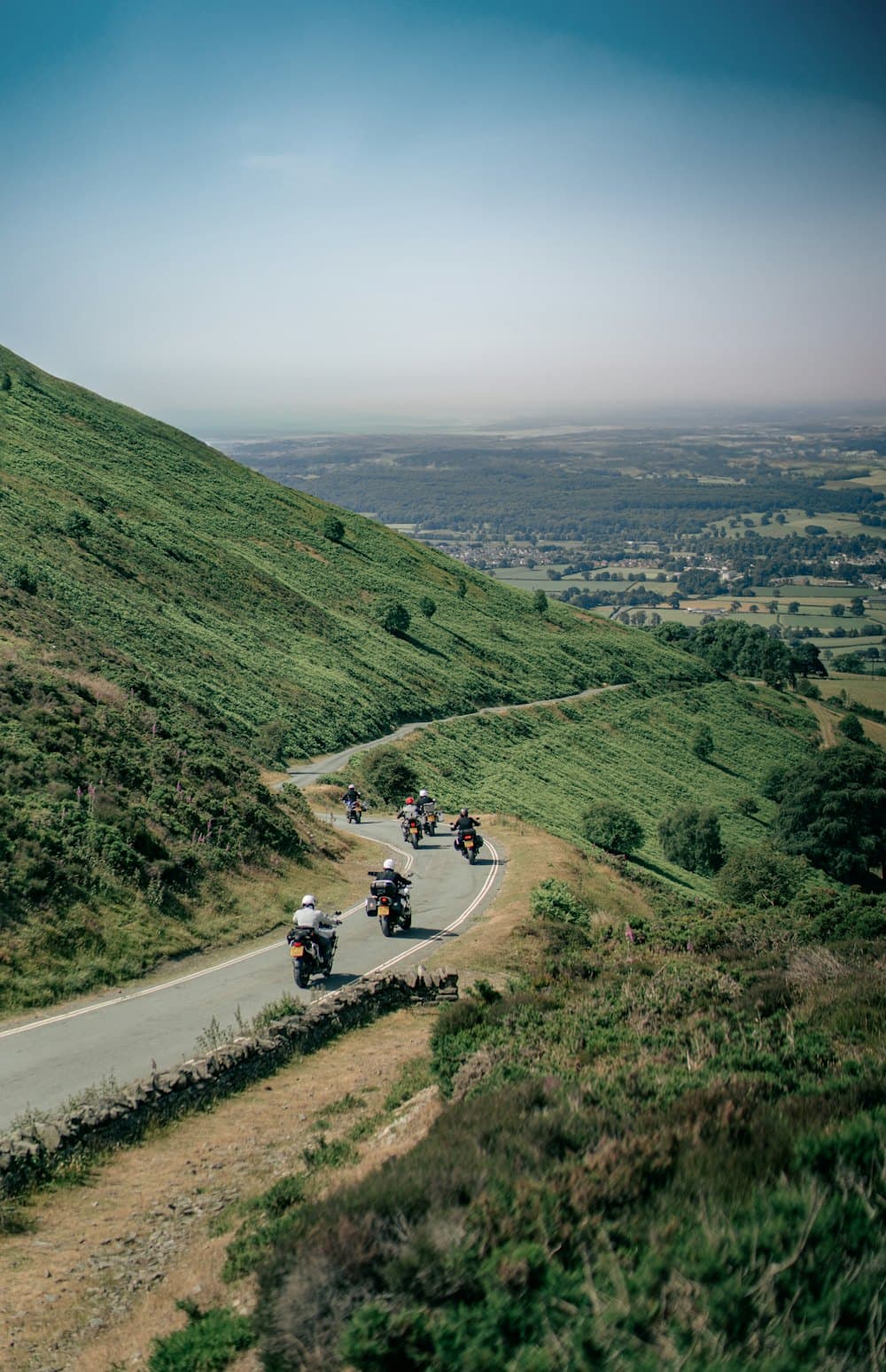 A pack of riders descending a winding valley road