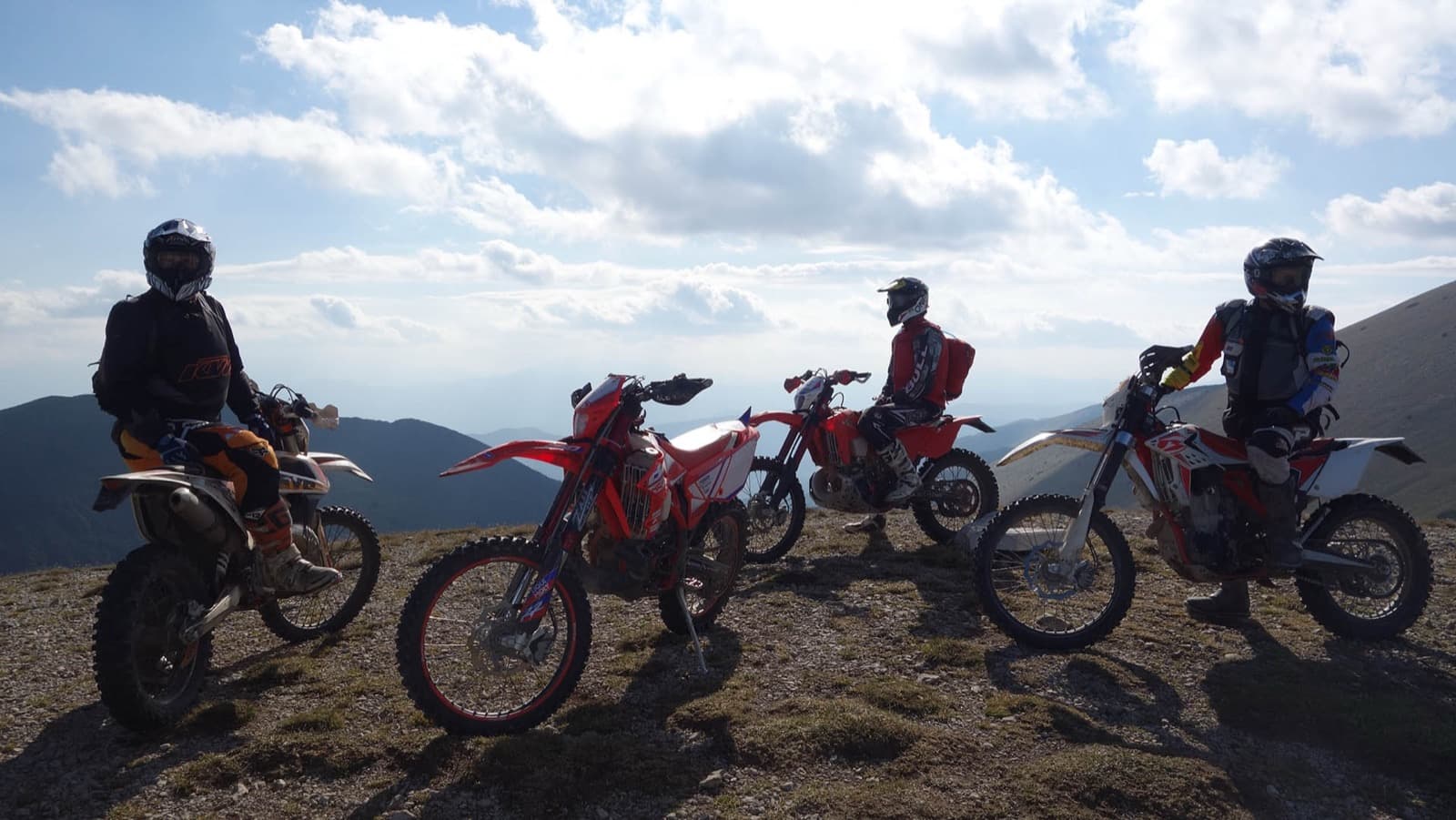 Dirt bikes and riders paused on a mountain summit