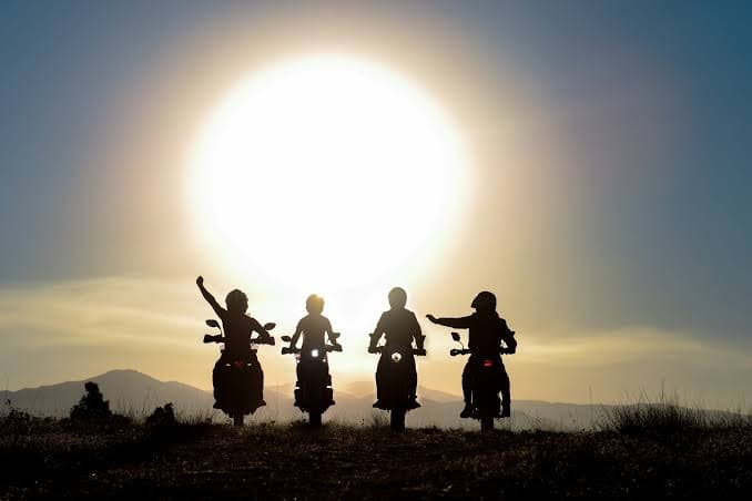 Four riders silhouetted against the setting sun