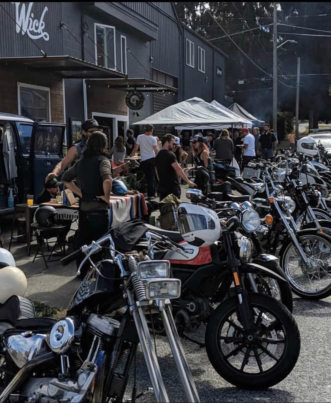 Bikes lined up outside a moto bar on a sunny bike night